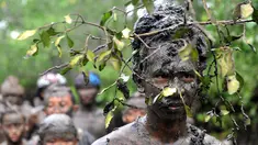 Warga Bali mengunakan akar pohon di kepalanya saat mengikuti tradisi mandi lumpur atau dikenal Mebuug-buugan di desa Kedonganan, Denpasar, Bali (10/3). Mebuug-buugan diadakan sehari usai hari raya Nyepi. (AFP/Sonny Tumbelaka)