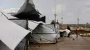 Tinggal di tenda usang dengan kondisi terpal yang compang-camping atau di tengah puing-puing bangunan. Tampak dalam foto, seorang perempuan Palestina pengungsi menyesuaikan terpal tenda keluarga saat wilayah tersebut dilanda hujan dan kondisi musim dingin yang dingin, di Kota Gaza pada 28 Desember 2025. (Omar AL-QATTAA/AFP)