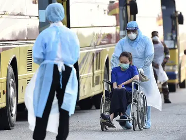 Petugas membawa warga Malaysia menggunakan kursi roda saat tiba setelah dievakuasi dari Wuhan, China akibat virus corona di Bandara Internasional Kuala Lumpur di Sepang, Selasa, (4/2/2020). Sejumlah 107 warga Malaysia dievakuasi Wuhan, China. (Muzzafar Kasim/Malaysia's Ministry of Health/AFP)