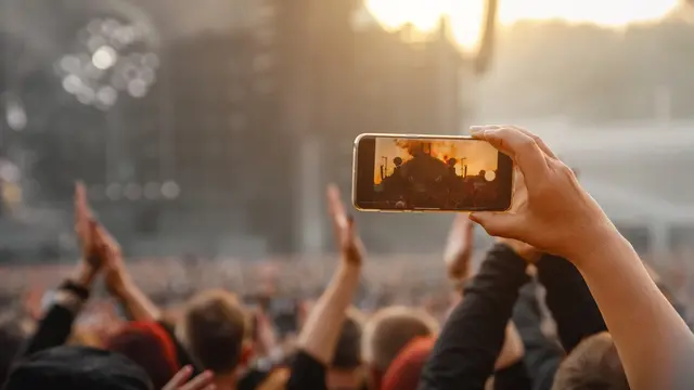 Ilustrasi nonton konser dan mengabadikan momen pakai smartphone
