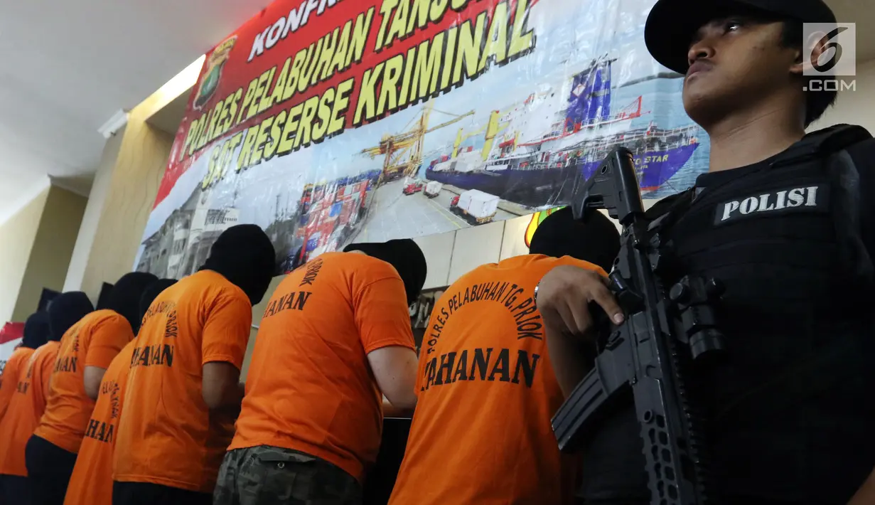 Polisi bersenjata menjaga tersangka kasus uang palsu saat dihadirkan dalam rilis di Polres Tanjung Priok, Jakarta, Kamis (11/7/2019). Para pelaku menjual uang asing palsu dengan nilai lebih rendah dari yang sebenarnya. (Liputan6.com/JohanTallo)