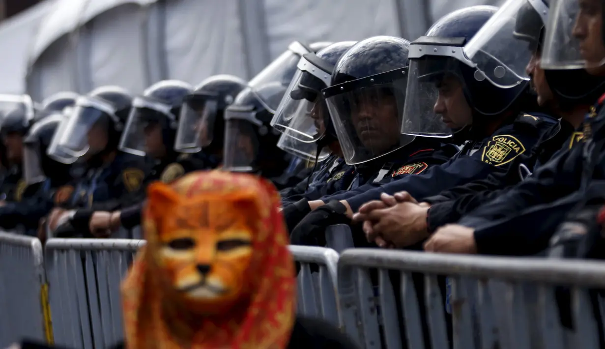 Petugas berjaga saat protes menandai ulang tahun sebelas bulan hilangnya 43 siswa yang hilang di Meksiko (26/8/2015). Para mahasiswa menghilang sejak 26 September 2014 di kota barat daya Iguala. (REUTERS/Henry Romero)