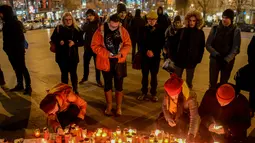 Sejumlah orang menyalakan lilin di depan foto jurnalis investigasi Slovakia Jan Kuciak di Wenceslas Square di Praha (26/2). Mereka berkumpul sambil menyalakan lilin untuk memberi penghormatan kepada Jan Kuciak. (AFP Photo/Michal Cizek)