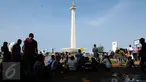 Sejumlah pengunjung beristirahat di bawah pohon yang ada di sekitar areal Monumen Nasional, Jakarta, Jumat (1/1/2016). Hari libur tahun baru 2016 dimanfaatkan ribuan warga untuk berwisata di kawasan Monumen Nasional. (Liputan6.com/Helmi Fithriansyah)