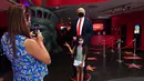 Seorang anak berfoto dengan sosok Donald Trump yang bermasker saat Madame Tussauds New York dibuka kembali di New York City, Kamis (27/8/2020). Patung lilin Donald Trump akan berada di pintu masuk untuk mengingatkan tentang protokol kesehatan, termasuk mengenakan masker. (Cindy Ord/Getty Images/AFP)
