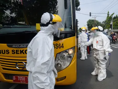 Petugas Dishub memakai baju APD akan menjemput korban yang diduga terjangkit Covid-19 menggunakan bus sekolah di Puskesmas Kebayuran Lama, Jakarta, Senin (6/7/2020). Bus sekolah tersebut selama liburan dibantukan untuk mengangkut pasien Covid-19 ke Wisma Atlet Kemayoran. (merdeka.com/Dwi Narwoko)