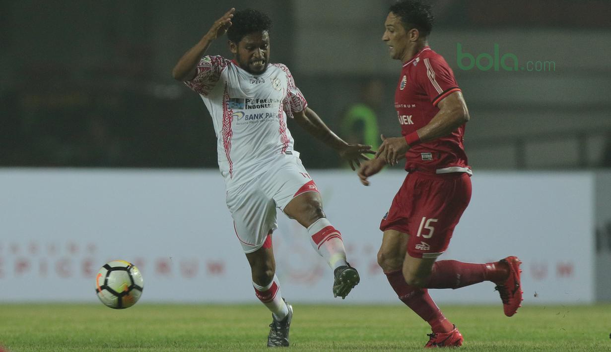 Pemain Persipura Jayapura, Emanuel Wanggai (kiri) menghalau bola dari kejaran pemain Persija, Addison Alves pada lanjutan Liga 1 Gojek bersama Bukalapak di Stadion Pakansari, Bogor, (25/5/2018).  Persija menang 2-0. (Bola.com/Nick Hanoatubun)