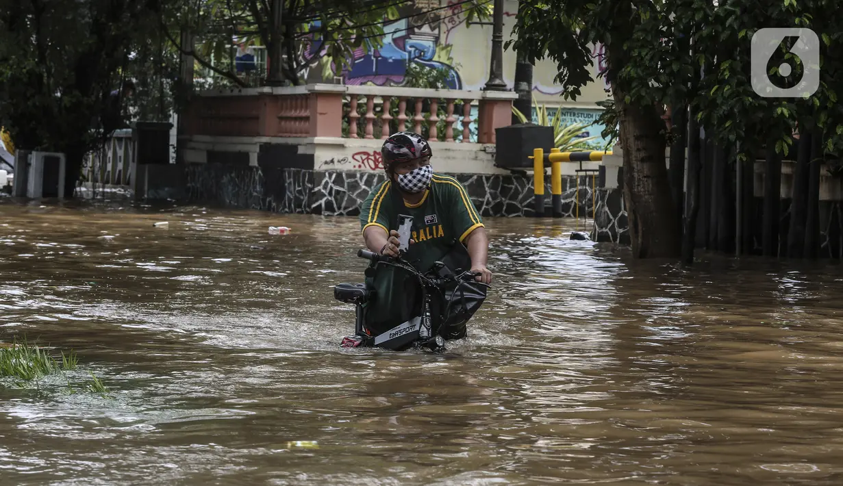 Warga menuntun sepedanya saat melewati banjir di kawasan Tendean Jakarta, Sabtu (20/2/2021). Curah hujan yang tinggi menyebabkan banjir setinggi orang dewasa di kawasan Tendean. (Liputan6.com/Johan Tallo)