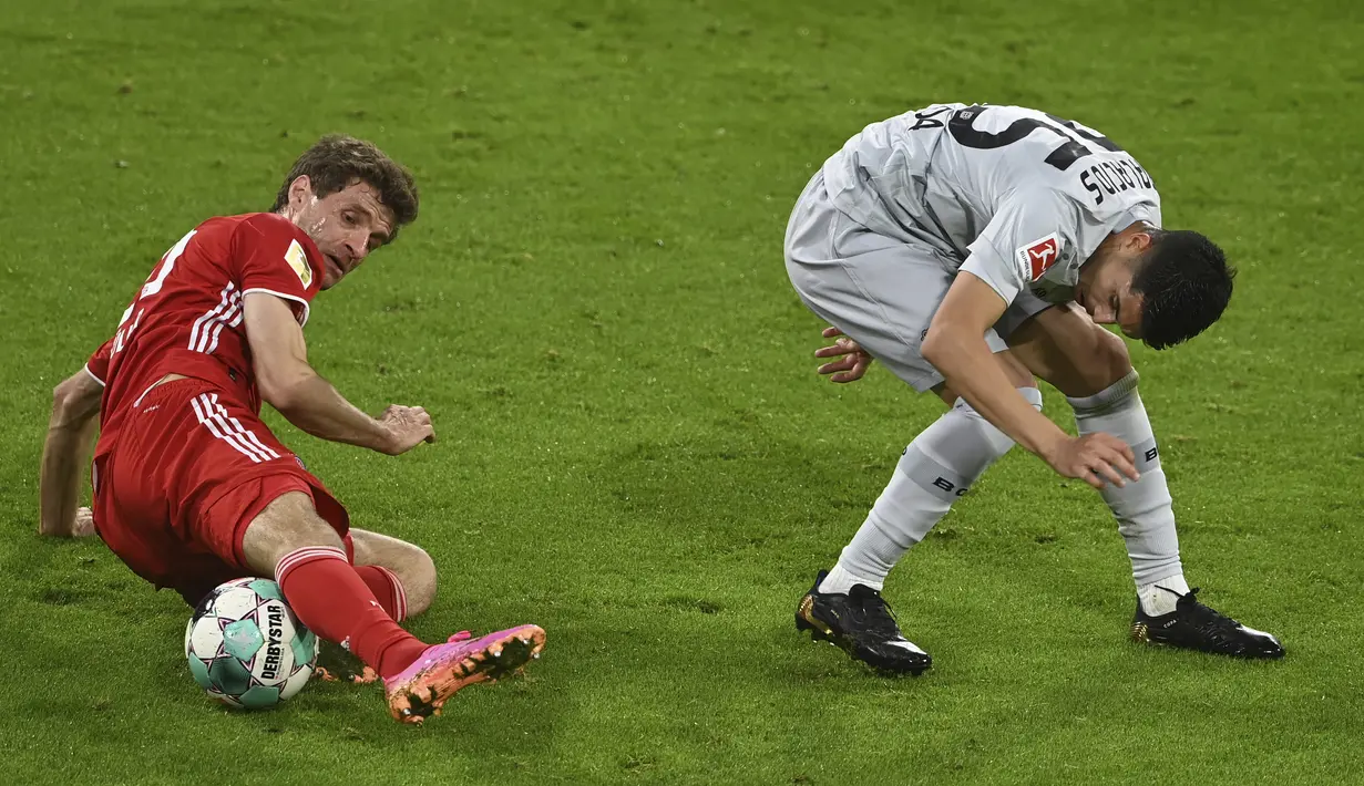 Pemain Bayern Munchen Thomas Mueller (kiri) berebut bola dengan pemain Bayer Leverkusen Exequiel Palacios pada pertandingan Bundesliga di Stadion Allianz Arena, Munchen, Jerman, Selasa (20/4/2021). Bayern Munchen menang 2-0. (Christof Stache, Pool via AP)