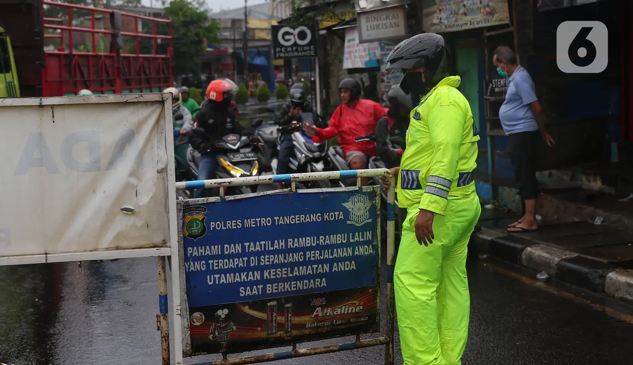 Petugas kepolisian melakukan penutupan jalan KH Hasyim Ashari, Kota Tangerang, Banten, Sabtu (16/7/2022). Intensitas curah hujan yang tinggi sejak Jumat (15/7) siang menyebabkan akses jalan Hasyim Ashari terputus karena terendam banjir setinggi 50 hingga 70 sentimeter. (Liputan6.com/Angga Yuniar)