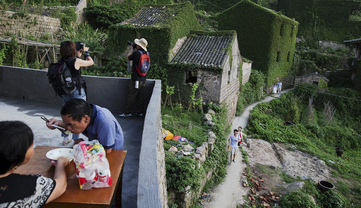 Sejumlah wisatawan tampak menikmati suasana di sebuah desa yang sudah ditinggalkan penghuninya, di Houtouwan, pulau Shengshan, China, 26 Juli 2015. Desa ini dulunya dihuni lebih dari 2.000 nelayan. (REUTERS/Damir Sagolj)