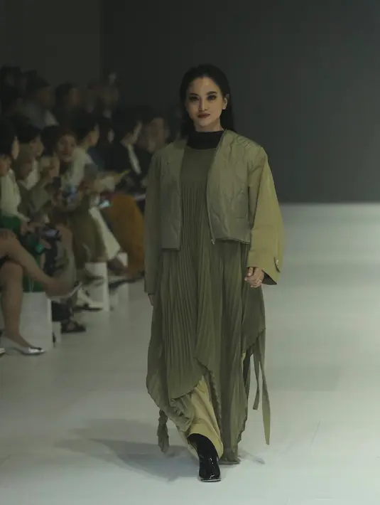 Ririn Ekawati tampil serba hijau army, dengan dress asimetris plisket dipadukan jaket crop dan celana warna serasi. [Fimela/Daniel Kampua]