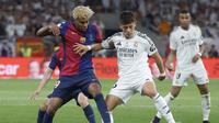 Pemain depan Barcelona asal Spanyol #19 Lamine Yamal dan gelandang Real Madrid asal Turki #15 Arda Guler berebut bola saat laga final Copa del Rey (Piala Raja) antara FC Barcelona dan Real Madrid CF di stadion La Cartuja di Seville pada Minggu (27/4/2025) dini hari WIB. (Pierre-Philippe MARCOU / AFP)