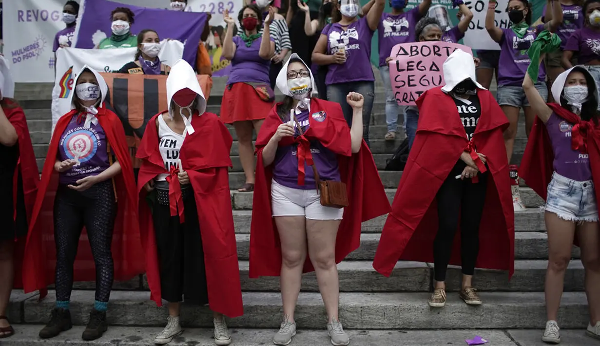 Pengunjuk rasa hak-hak aborsi berpakaian karakter meneriakkan slogan "The Handmaid's Tale" selama demonstrasi yang menandai Hari Dekriminalisasi Aborsi di Amerika Latin dan Karibia di luar majelis legislatif negara bagian di Rio de Janeiro, Brasil, Senin (28/9/2020). (AP Photo/Silvia Izquierdo)