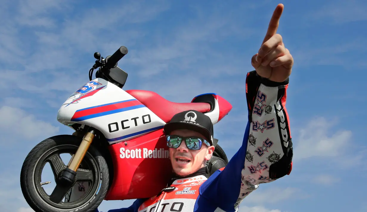Pembalap MotoGP Scott Redding berpose dengan motor listrik mini saat acara jumpa pers jelang MotoGP Jepang di sirkuit Twin Ring Motegi, Jepang (12/10). (AP Photo / Shizuo Kambayashi)