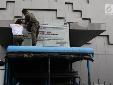 Petugas Satpol PP menyegel Diskotek Exotic dengan memasang banner penutup di Mangga Besar, Jakarta, Kamis (19/4). Pemprov DKI menutup Diskotek Exotic setelah ditemukan pengunjung yang meninggal diduga akibat overdosis narkoba. (Liputan6.com/Arya Manggala)