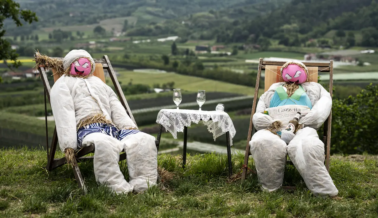<p>Sebuah gambar pada 3 Mei 2022 menunjukkan dua orang-orangan sawah di ladang selama pekan raya tahunan di desa Castellar, Italia utara, dekat Cuneo. Warga menghias orang-orangan sawah layaknya manusia. Seperti mengenakan gaun, kemeja, topi, dan kaca mata lalu menempatkannya di kebun, halaman, ladang serta jalan.(MARCO BERTORELLO / AFP)</p>