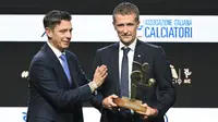 Wasit Italia, Daniele Orsato, berpose di atas panggung setelah menerima penghargaan 'Wasit Terbaik' dari Gianluca Rocchi (kiri) selama acara penghargaan Italian Footballers' Association (AIC) 2023 pada 4 Desember 2023 di Milan. (Marco BERTORELLO/AFP)