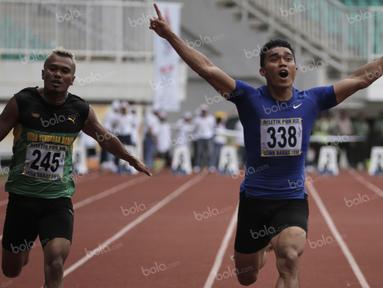 Atlet Sumatra Barat, Yaspi Boby (kanan), meraih emas lari 100m putra PON XIX Jawa Barat 2016 mengalahkan atlet NTB, Iswandi (tengah), dalam final di Stadion Pakansari, Bogor, Kamis (22/9/2016). (Bola.com/Arief Bagus)