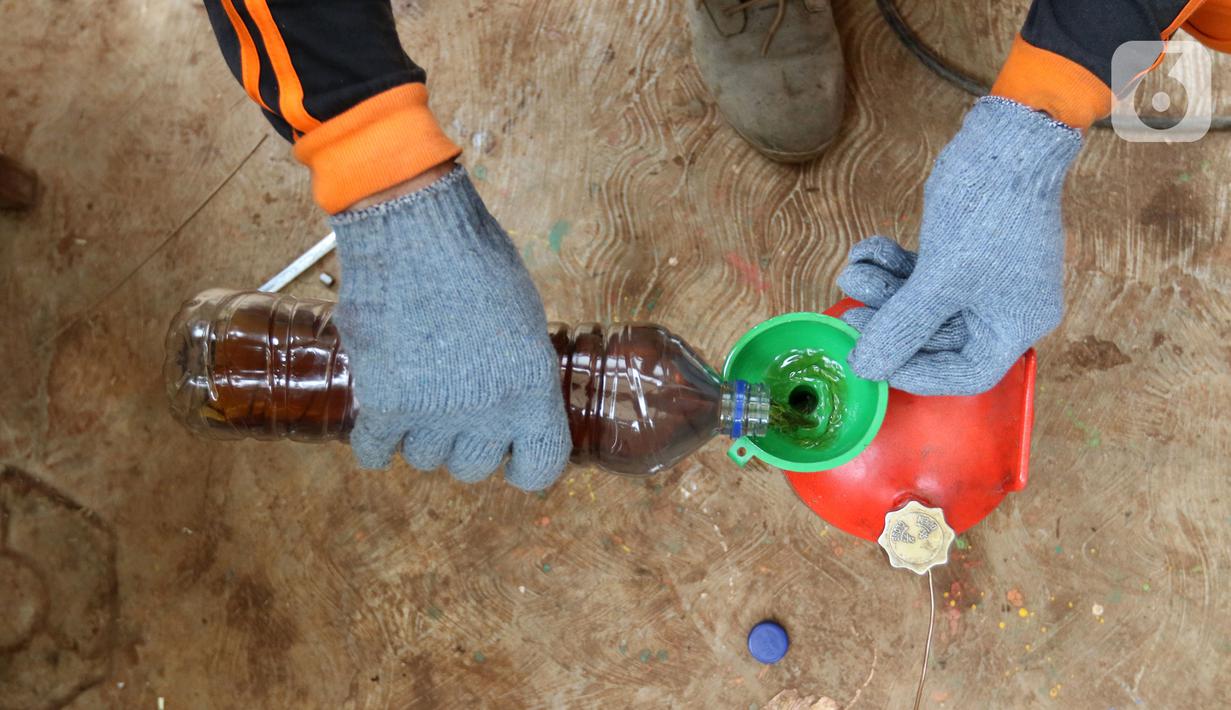 Petugas PPSU Kelurahan Kota Bambu Selatan menuangkan solar hasil olahan ke dalam tabung minyak di Bank Sampah Hasil Berkah, Jakarta, Kamis (11/11/2021). Sampah plastik dikonversi menjadi solar menggunakan alat mesin pirolisis untuk mengurangi pencemaran lingkungan. (Liputan6.com/Herman Zakharia)