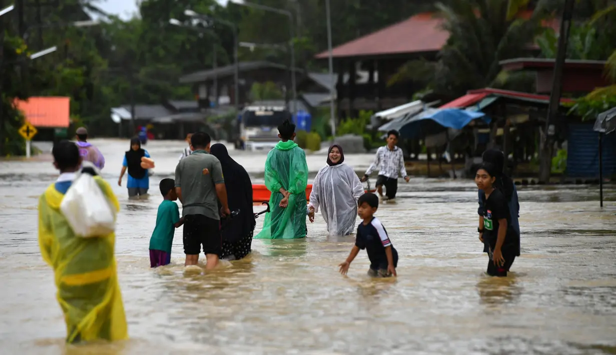 Warga berjalan melewati banjir menyusul hujan lebat di distrik Ran-ngea di provinsi Narathiwat, Thailand selatan (26/2/2022).  Lebih dari 7.200 rumah tangga di 195 desa telah terkena dampak, dengan 6.891 rumah rusak, karena Sungai Sungai Kolok yang diguyur hujan terus meluap. (AFP/Madaree Tohlala)