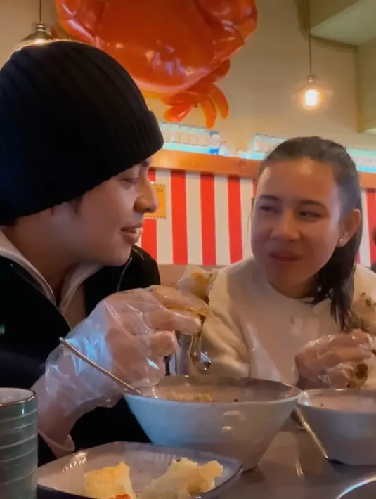 Keduanya membagikan keseruan bersama di Korea Selatan seperti kulineran. Saat makan kepiting, Shenina mengenakan sweater hitam dihiasi mutiara. Dan Angga mengenakan jaket hitam. [@angga]