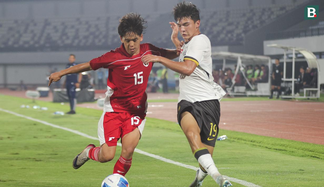 Pemain Timnas Indonesia U-17, Miraj Rizky mencoba mempertahankan bola dari rebutan pemain China U-17, Ailikamu Yilihong dalam pertandingan uji coba internasional di Indomilk Arena, Tangerang, pada Rabu (11/2/2026) malam WIB. (Bola.com/Abdul Aziz)
