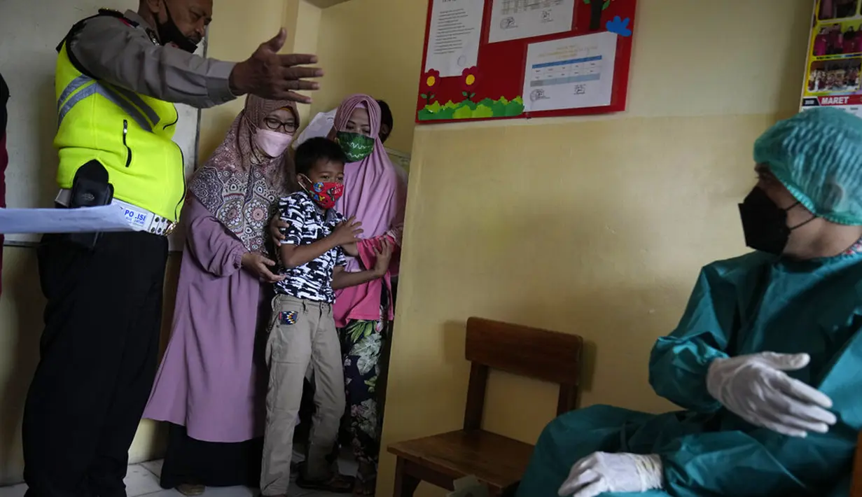 Orangtua, guru, dan polisi mencoba menenangkan seorang siswa saat akan disuntik pada kampanye vaksinasi COVID-19 di sebuah sekolah untuk anak-anak berkebutuhan khusus di Depok, Jawa Barat, Selasa (11/1/2022). Kampanye vaksinasi ini dilakukan oleh Polri. (AP Photo/Dita Alangkara)