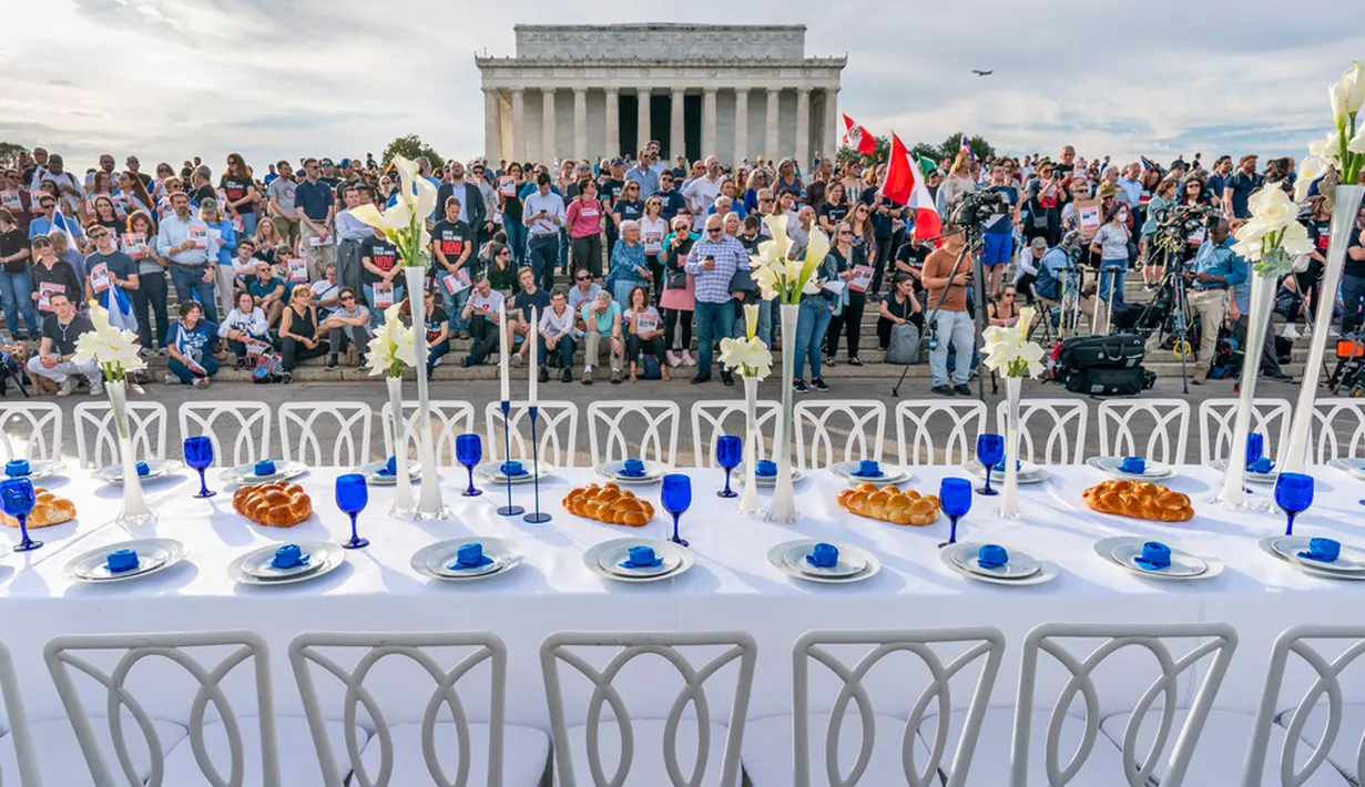 Para pendukung Israel berdiri di depan meja hari shabbat yang kosong sebagai simbol sandera yang diambil selama serangan Hamas terhadap Israel di Lincoln Memorial, Washington, Amerika Serikat, Jumat (27/10/2023). Lebih dari dua minggu setelah Hamas menculik warga dan tentara Israel, keluarga sandera yang ditahan di Gaza telah memulai tur internasional. (AP Photo/J. Scott Applewhite)
