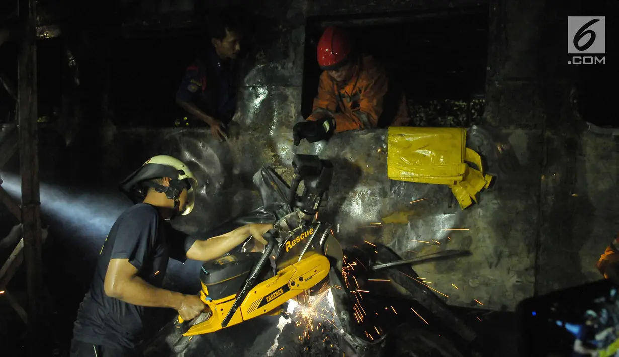 Petugas memotong minibus yang ringsek puing usai  kecelakaan kereta api di perlintasan Kramat, Senen, Jakarta, Selasa (13/6). Petugas menemukan dua orang yang tewas terbakar. (Liputan6.com/Helmi Afandi)