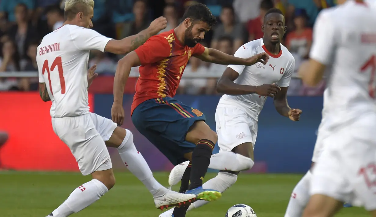 Striker Spanyol, Diego Costa, berusaha melewati gelandang Swiss, Valon Berhami, pada laga persahabatan di Stadion La Ceramica, Vila-real, Minggu (3/6/2018). Kedua negara bermain imbang 1-1. (AFP/Jose Jordan)