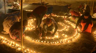 Umat Hindu India menyalakan lampu minyak untuk perayaan tradisional Magh Mela di Sangam, India (2/1). Magh Mela adalah sebuah festival tahunan yang digelar umat Hindu di India. (AFP Photo/Sanjay Kanojia)