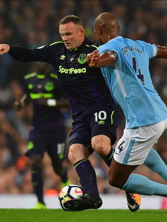 Striker Everton Wayne Rooney berusaha melewati bek Manchester City Vincent Kompany saat pertandingan Liga Primer Inggris di Stadion Etihad, Manchester (21/8). (AFP/Anthony Devlin)