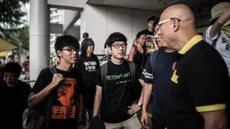 Joshua Wong (kiri) dan Nathan Law (tengah) berbincang dengan pendukungnya di luar pengadilan, Hong Kong, Cina, Jumat (28/8/2015). Nathan Law dan Joshua Wong berperan dalam aksi mahasiswa dan pelajar di Hong Kong 2014 lalu. (AFP PHOTO/Philippe Lopez)