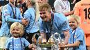 Pemain Manchester City, Kevin De Bruyne bersama kedua anaknya berpose dengan trofi Liga Champions setelah mengalahkan Inter Milan di Ataturk Olympic Stadium, Istanbul, Turki, 10 Juni 2023. De Bruyne diketahui merupakan kapten dengan gaji tertinggi di Liga Inggris. Ia mendapatkan bayaran sebesar 400 ribu pounds per pekan di Etihad Stadium. Sementara itu, pemain Belgia tersebut masih memiliki kontrak hingga 2025 mendatan. (AFP/Paul Ellis)