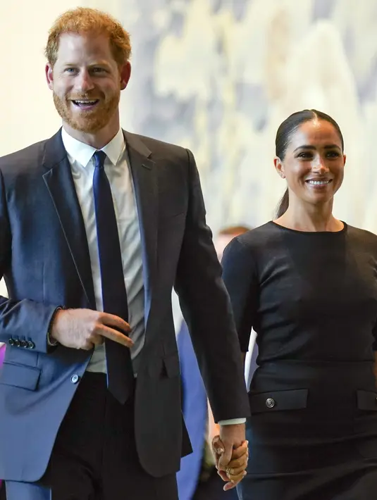 <p>Meghan Markle didampingi suaminya Pangeran Harry tersenyum saat tiba di markas PBB (18/7/2022). Meghan dan Harry tampak kompak mengenakan pakaian serbahitam. (AP Photo/Seth Wenig)</p>