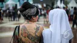 Sejumlah wajah nyentrik bermunculan di acara Indonesia Greaser Party 2015, Plaza Barat Senayan, Jakarta, Minggu (12/4/2015). Tampak seorang wanita memperlihatkan punggungnya yang bertattoo. (Liputan6.com/Faizal Fanani)