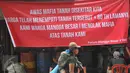 Seorang ibu menggendong anaknya berjalan di depan spanduk penolakan di kawasan jalan Mangga Besar, Jakarta, Senin (22/8). Spanduk itu dipasang warga RW2 Kelurahan Mangga Besar sebagai aksi menolak penggusuran rumah mereka. (Liputan6.com/Gempur M Surya)
