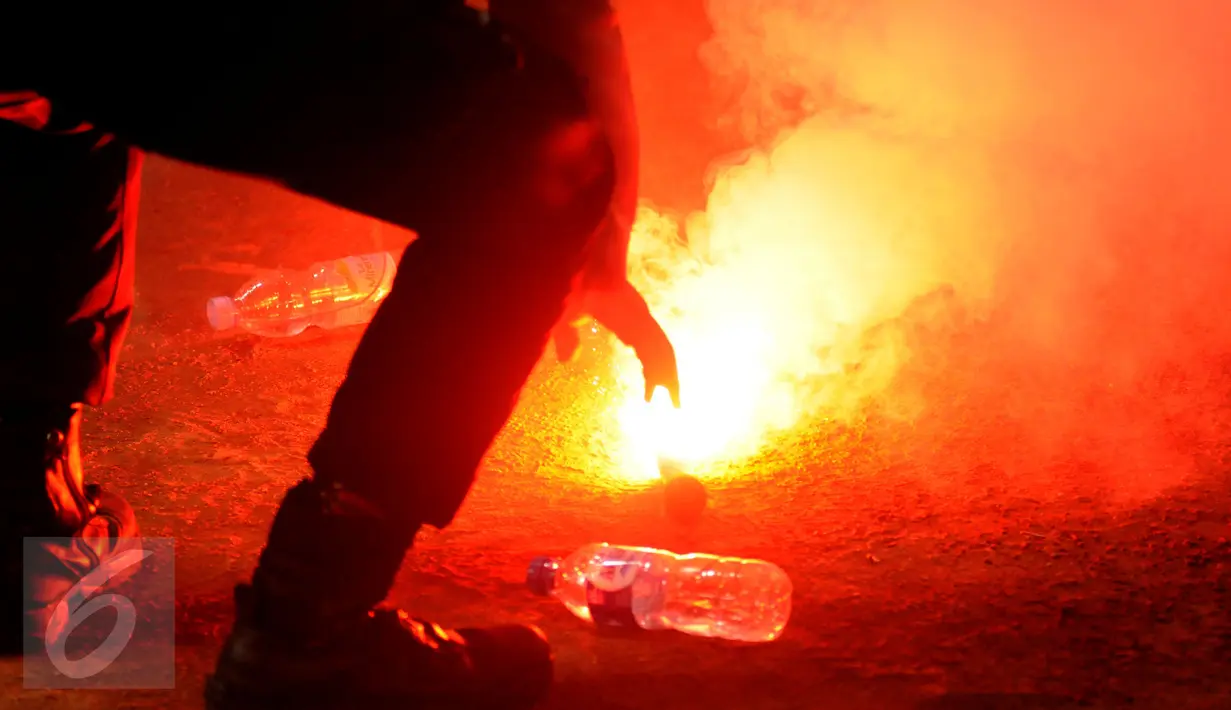 Personel kepolisian memadamkan flare yang dilempar saat laga final Piala Bhayangkara 2016 antara Arema vs Persib di Stadion GBK Jakarta, Minggu (3/4/2016). Laga diwarnai aksi protes dari suporter dan official Persib. (Liputan6.com/Helmi Fithriansyah)