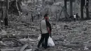 <p>Seorang pria Palestina yang membawa kantong plastik belanja berbicara dengan seorang wanita ketika mereka berdiri di tengah puing-puing setelah serangan udara Israel di lingkungan al-Rimal, Kota Gaza, pada 10 Oktober 2023. (MOHAMMED ABED/AFP)</p>