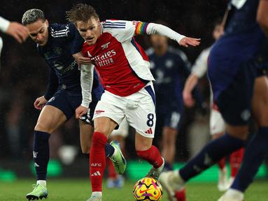 Gelandang Manchester United, Antony (kiri) berebut bola dengan pemain Arsenal Martin Odegaard pada lanjutan Liga Premier Inggris 2024/2025 di Stadion Emirates, London pada Rabu 4 Desember 2024 waktu setempat atau Kamis 5 Desember 2024 dini hari WIB. (Adrian Dennis/AFP)