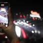 Pengunjung mengabadikan dengan ponselnya konser musik pada acara "Pestapora 2022" di Gambir Expo Kemayoran, Jakarta, Sabtu (24/9/2022). Pada acara pertunjukan musik Indonesia yang berlangsung 23-25 September 2022 tersebut menghadirkan enam panggung pertunjukan dengan menampilkan berbagai musisi tanah air.  (Liputan6.com/Herman Zakharia)
