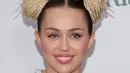 Miley hadir dengan menggunakan pakaian hasil rancangan Prada dengan skirt garis-garis dan crop top berwarna birunya yang berbentuk pita. Tampil maksimal, Miley hadir dengan senyuman menawan. (AFP/Bintang.com)