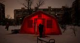 Seorang pria berada di luar tenda darurat tempat orang-orang dapat menghangatkan diri setelah serangan udara rutin Rusia terhadap fasilitas energi negara itu di tengah musim dingin, Kyiv, Ukraina, Selasa 13 Januari 2026. Militer Rusia kembali meluncurkan serangan udara besar-besaran ke Ukraina, Selasa (13/1/2026). (AP Photo/Danyil Bashakov)