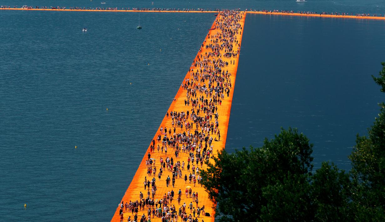 Ribuan orang berjalan di atas sebuah instalasi "The Floating Piers" yang merupakan karya seniman Bulgaria, Christo Vladimirov Javacheff di Danau Iseo, Italia, (24/6). Karya menakjubkan ini diharapkan dapat menarik wisatawan. (REUTERS/Stefano Rellandini)