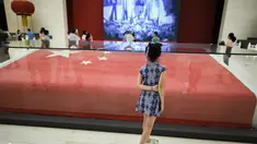 Seorang gadis melihat bendera nasional Tiongkok yang dikibarkan pada 1 Oktober 1949 di Lapangan Tiananmen di Museum Nasional China di Beijing (22/8/2019). Negara itu akan merayakan peringatan ke-70 berdirinya Pendirian Republik RakyatTiongkok pada tanggal 1 Oktober 2019. (AFP Photo/Wang Zhao)