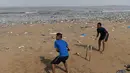 Dua pemuda India bermain kriket dengan dipenuhi sampah plastik di pantai Juhu di Mumbai, (2/6). (AFP PHoto/Punit Paranjpe)
