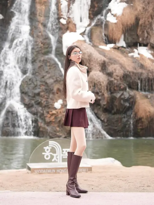 Untuk melengkapi penampilannya, ia memakai sepatu boots kulit berwarna marun yang senada dengan roknya. Boots tinggi ini tidak hanya memberikan perlindungan dari dinginnya cuaca, tetapi juga menambah sentuhan elegan dan stylish pada keseluruhan look-nya. Rambut panjangnya yang dibiarkan tergerai dengan sedikit gelombang alami membuat penampilannya semakin effortless dan classy. [@sabrinachairunnisa_].