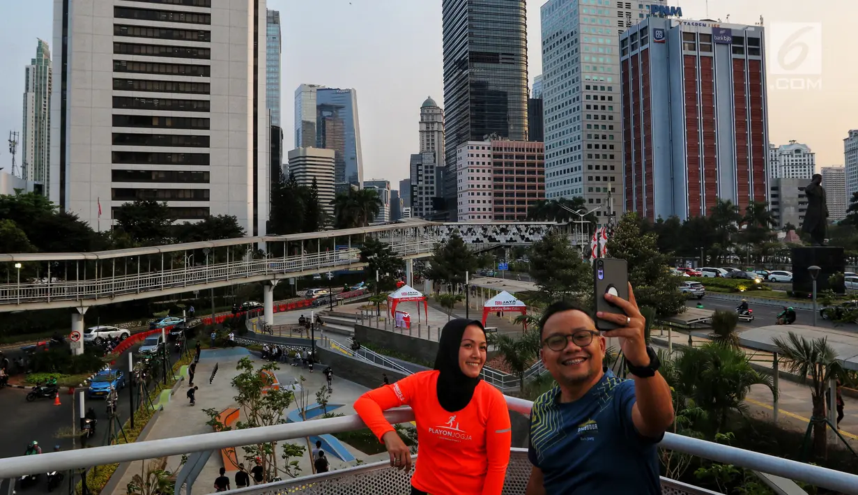 Warga berswafoto dengan latar belakang Taman Spot Budaya, di Dukuh Atas, Jakarta, Selasa (20/08/2019). Taman Spot Budaya Dukuh Atas ini merupakan salah satu program Pemprov DKI menyediakan ruang terbuka hijau ketiga untuk memberikan ruang interaksi kepada masyarakat. (Liputan6.com/Johan Tallo)