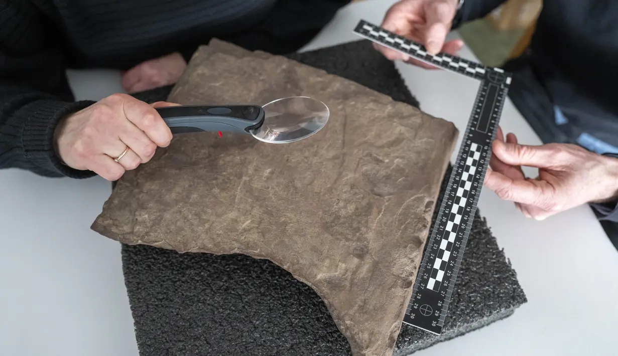 Para peneliti memeriksa runestone yang ditemukan di Tyrifjorden, di Museum Sejarah Budaya di Oslo, pada 12 Januari 2023. Dikatakan, temuan itu "di antara prasasti rahasia tertua yang pernah ditemukan" dan "runestone tertua yang dapat didata di dunia." (Javad Parsa/NTB Scanpix via AP)